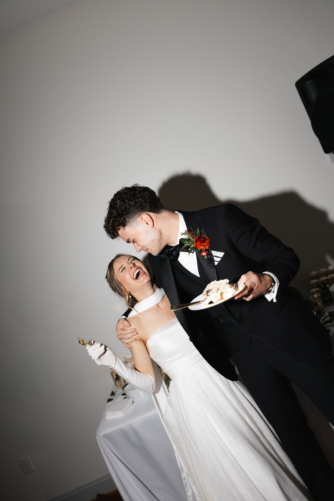 Laughing bride and groom celebrating after cutting their wedding cake at the reception.