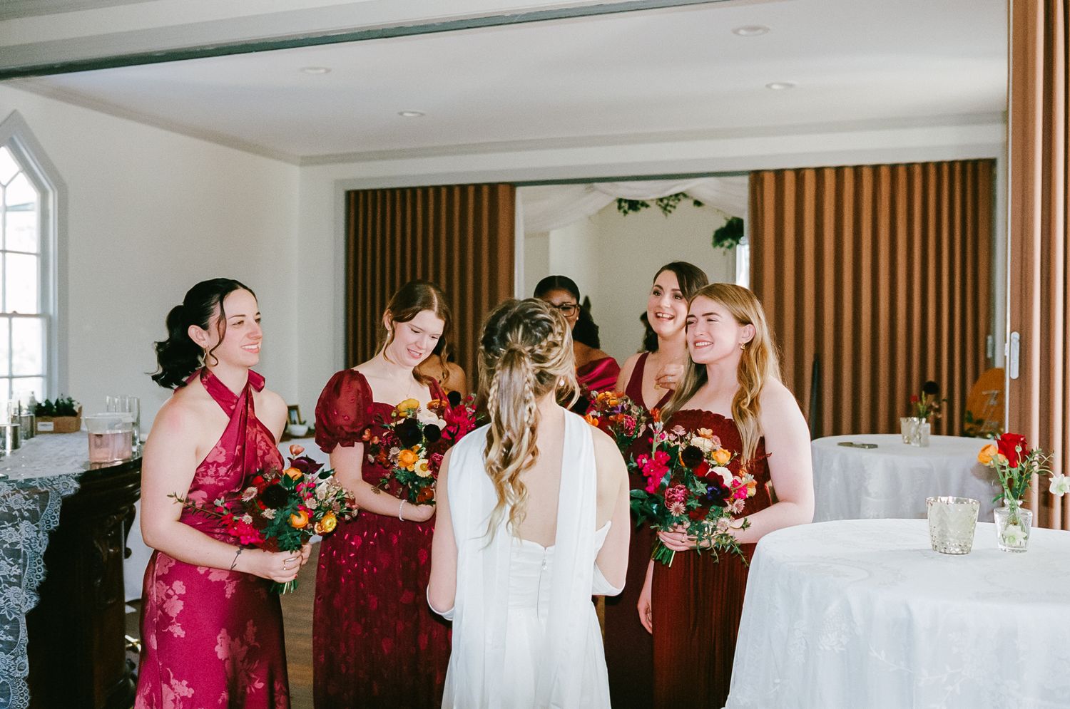 Bride in white gown surrounded by bridesmaids in red dresses at wedding reception photographed on 35mm film.