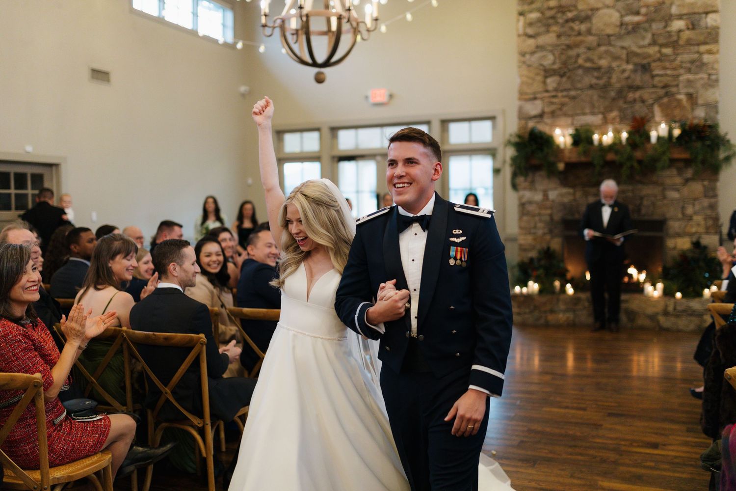 Joyful bride and groom in military uniform walk back down the aisle after their ceremony.