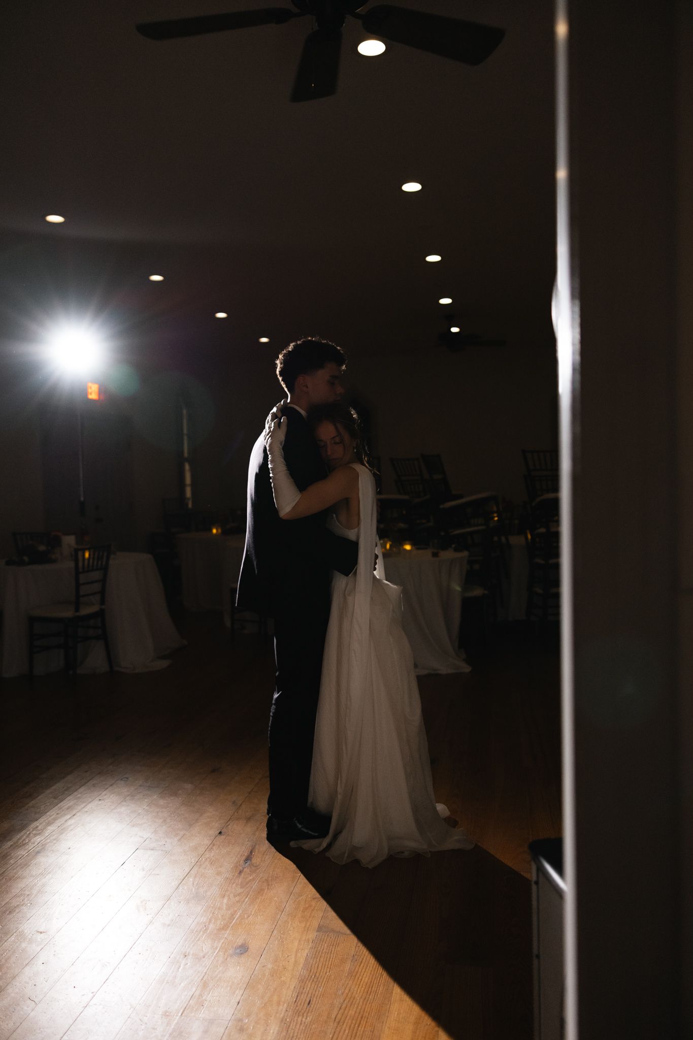 Bride and groom sharing an intimate first dance in a softly lit wedding venue.