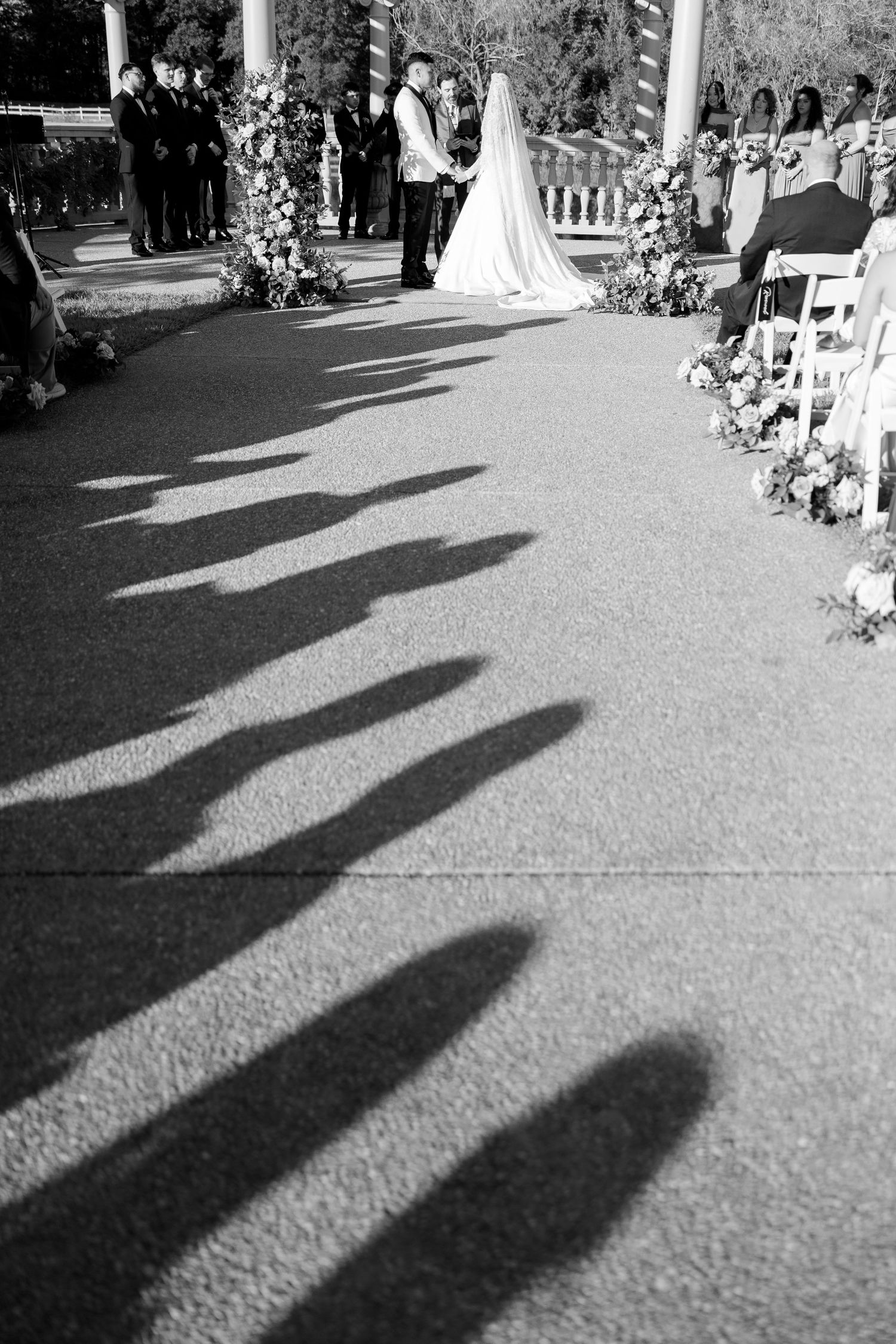 Black and white photo of wedding ceremony shadows cast on aisle with couple at altar.