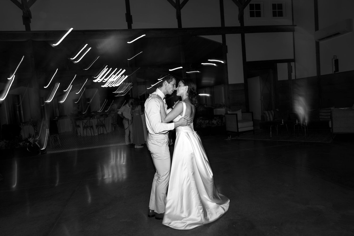 Black and white romantic first dance photo of bride and groom kissing on dance floor.