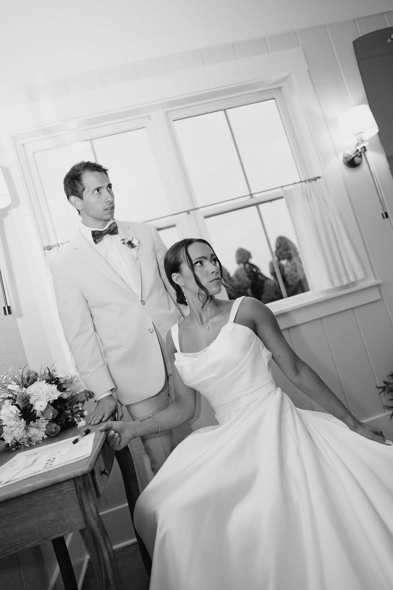 Black and white portrait of bride and groom at signing table during intimate wedding ceremony.