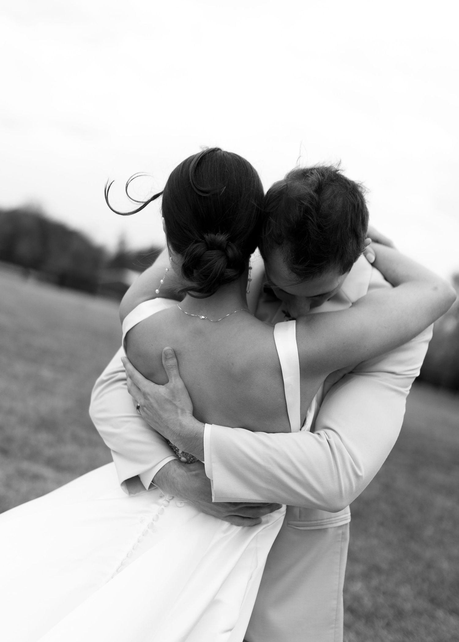 Black and white photo of bride and groom sharing an emotional embrace in an open field.