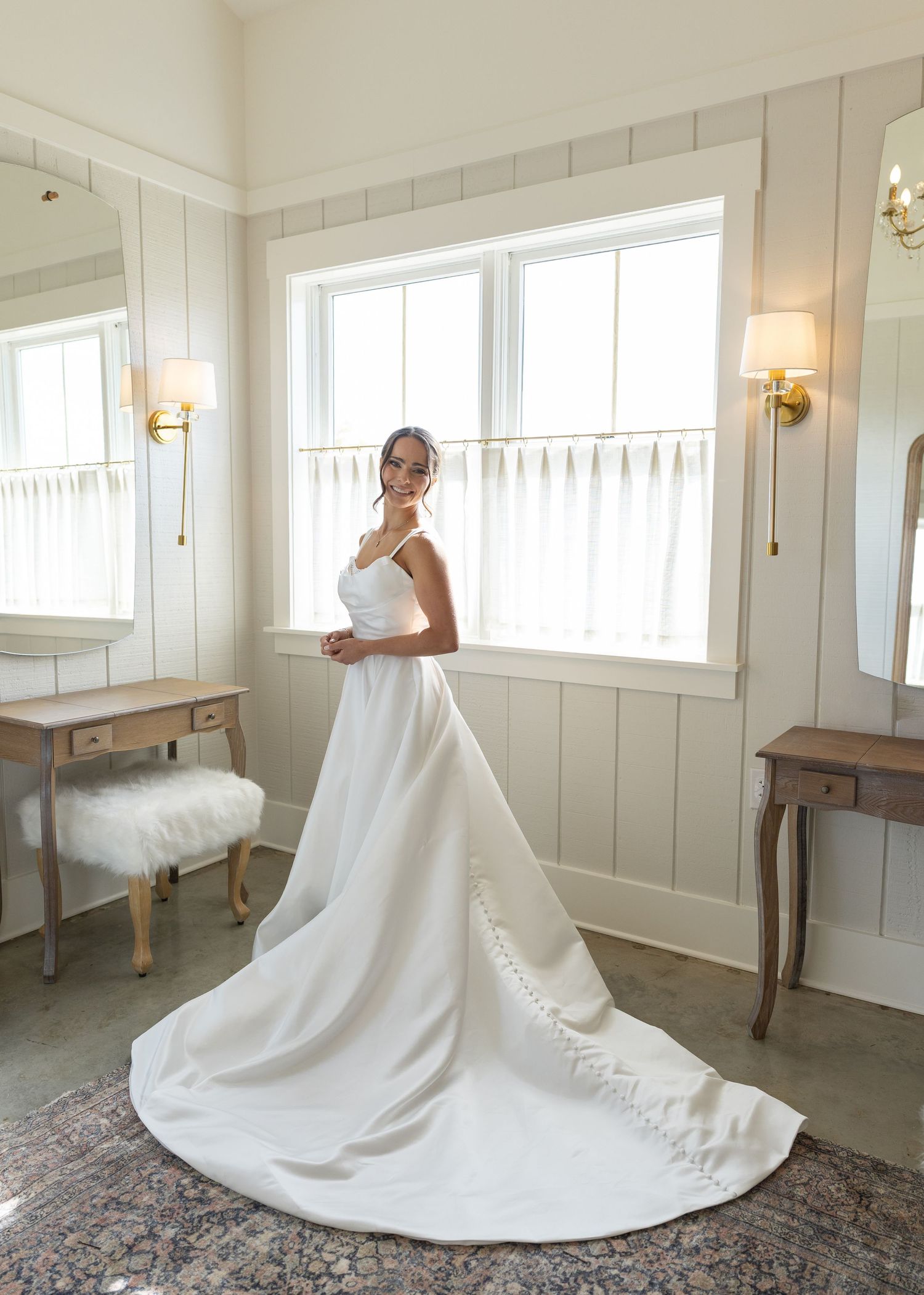 Bride in stunning white ball gown with long train posing in bright bridal suite.