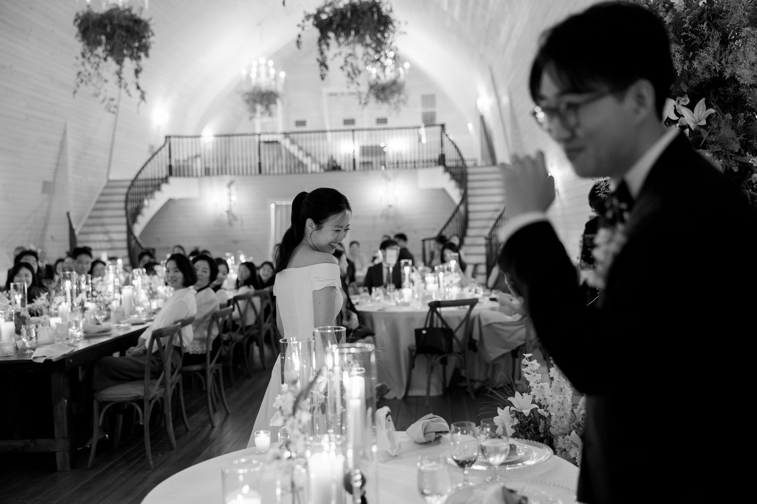 Elegant black and white wedding reception with candlelit tables and guests in grand venue.