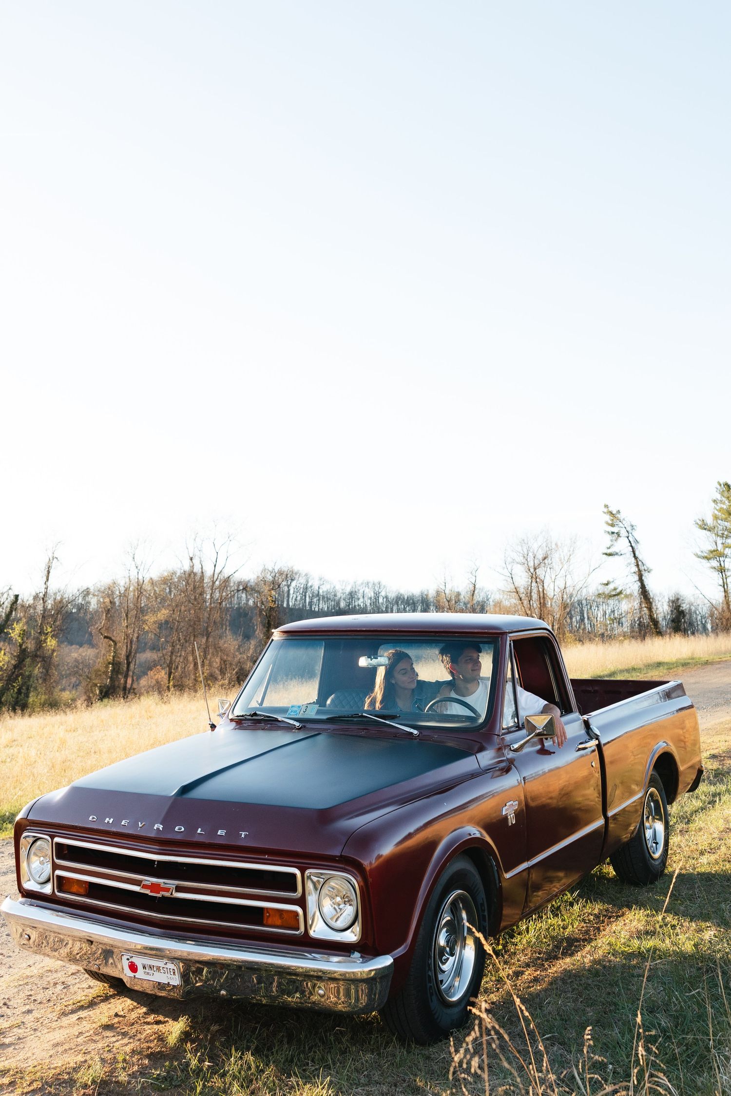 Classic burgundy Chevrolet C10 pickup truck parked in an open field on a clear day.