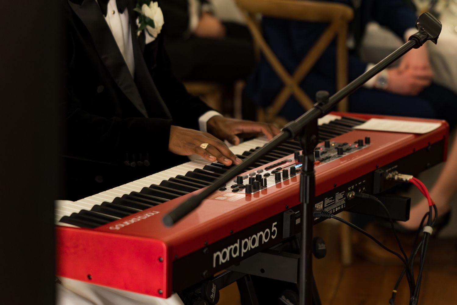 Musician plays a red Nord Piano 5 keyboard at an elegant wedding reception performance.