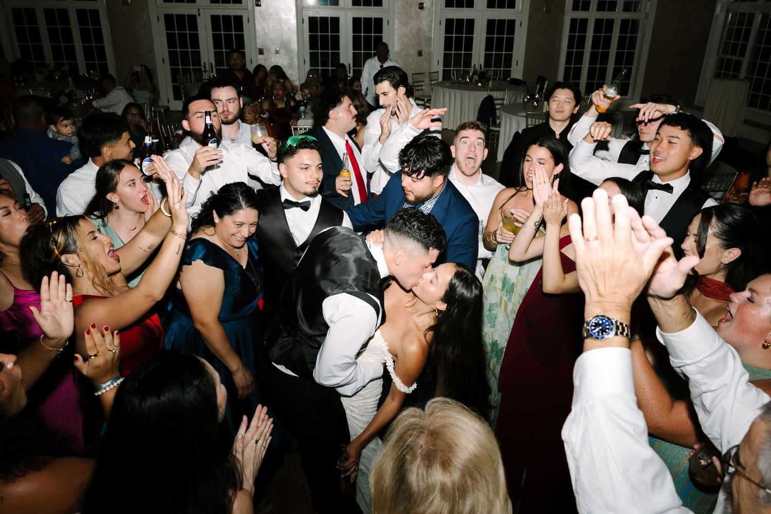 Guests celebrate on the dance floor at a lively wedding reception in formal attire.