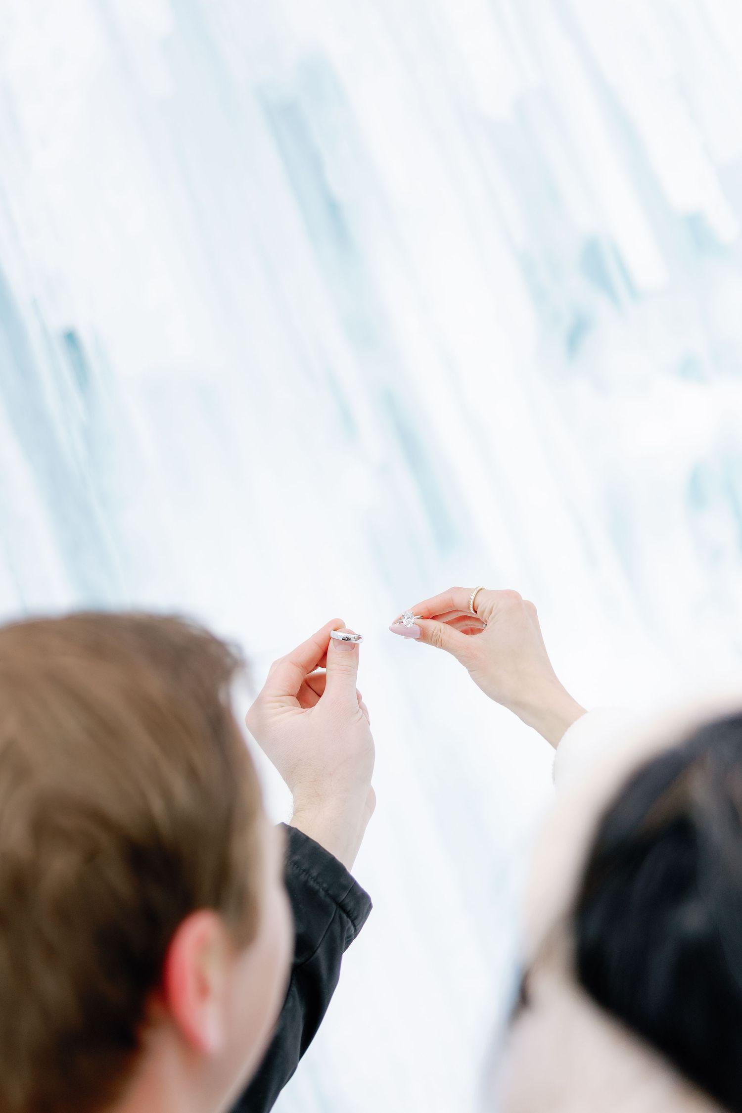 Close-up of couple admiring an engagement ring in front of a frozen ice wall backdrop.