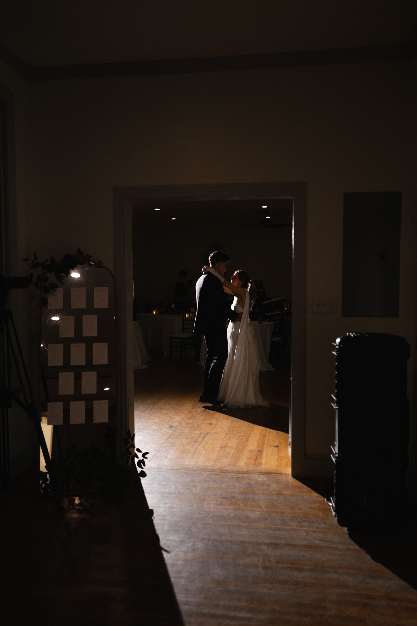 Silhouette of bride and groom sharing a romantic first dance in a softly lit doorway at their wedding reception.