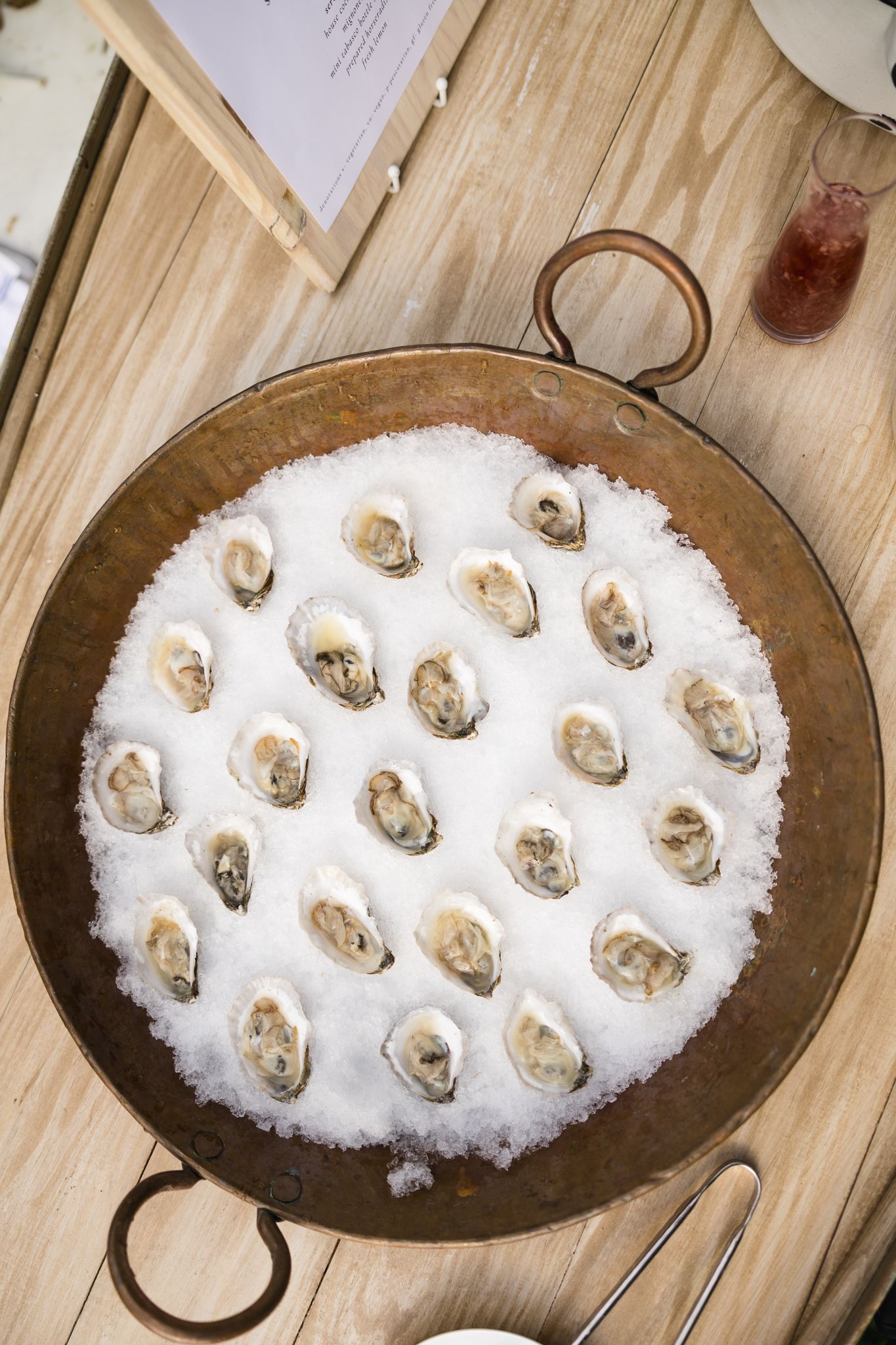 Fresh oysters on ice served in a rustic copper pan at wedding cocktail hour.