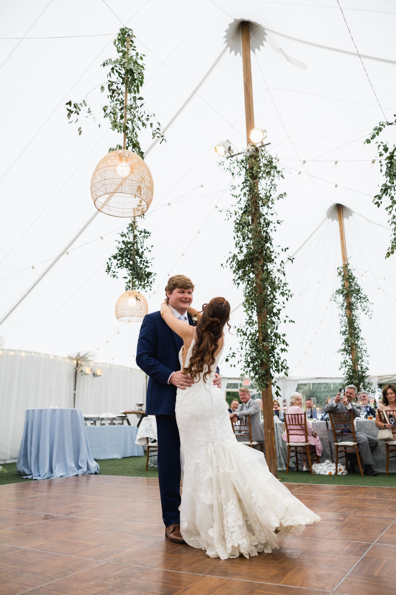 Bride and groom share first dance under sailcloth tent with greenery-wrapped poles.