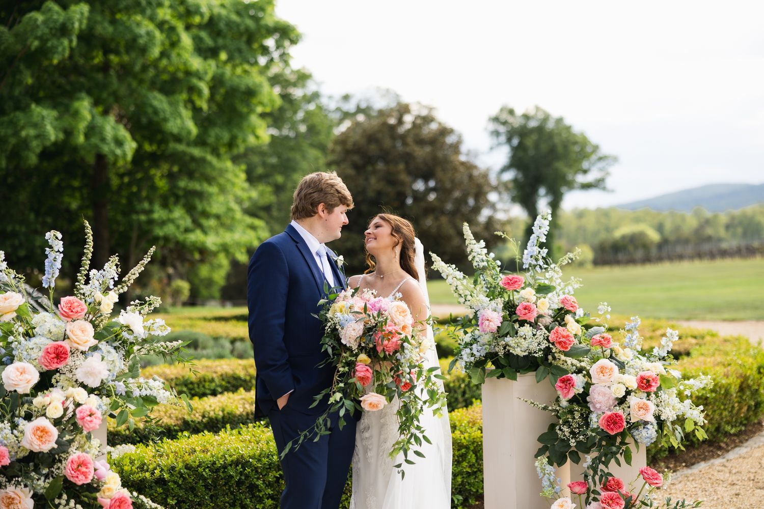 Bride and groom share romantic moment surrounded by pink and white floral ceremony arrangements.