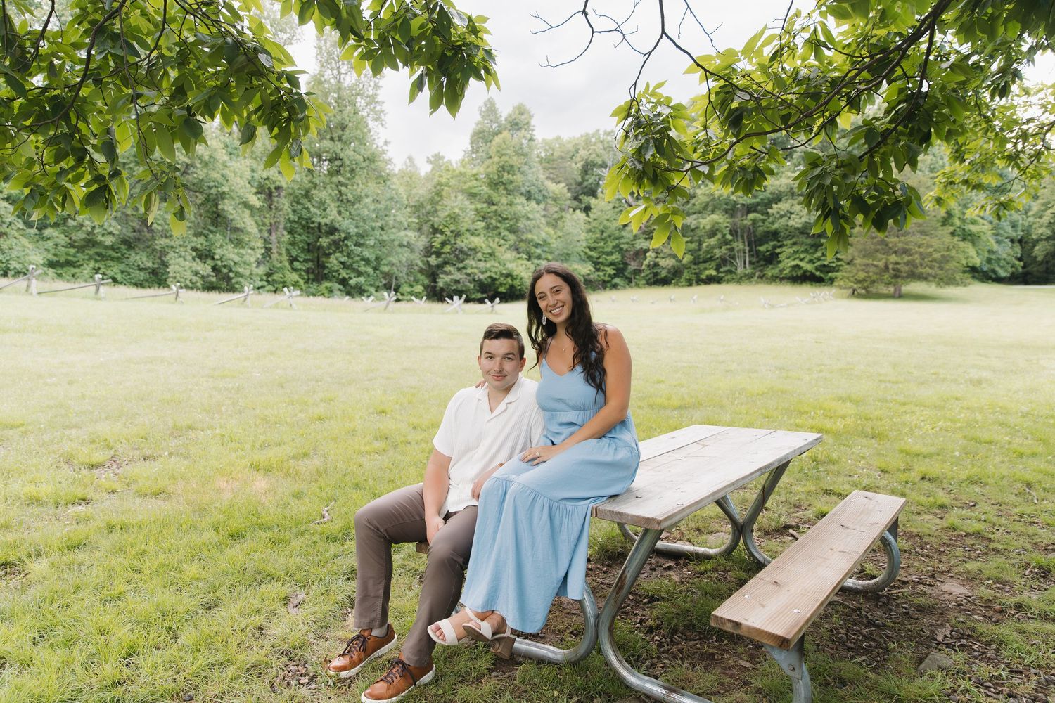 Couple sitting together at picnic table in lush green park.