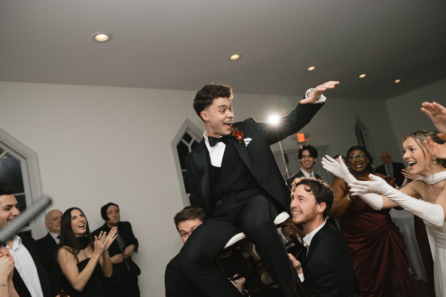 Groom is lifted by groomsmen while celebrating on the dance floor at a lively wedding reception.