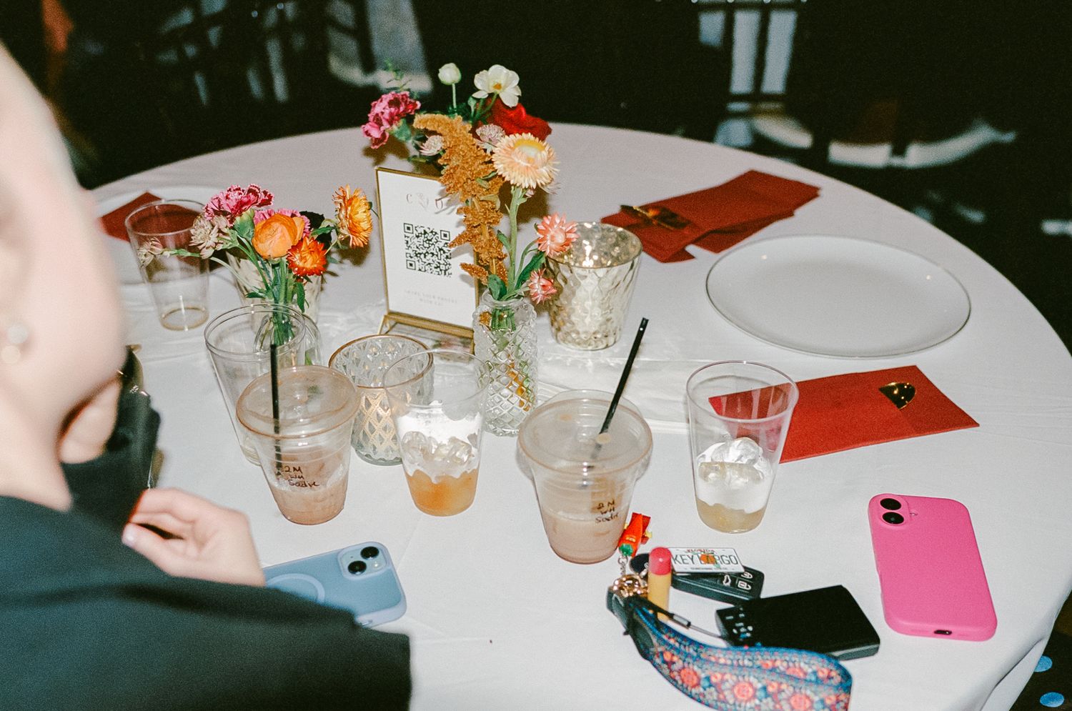 Overhead view of round reception table with colorful floral centerpiece and drinks photographed on 35mm film.