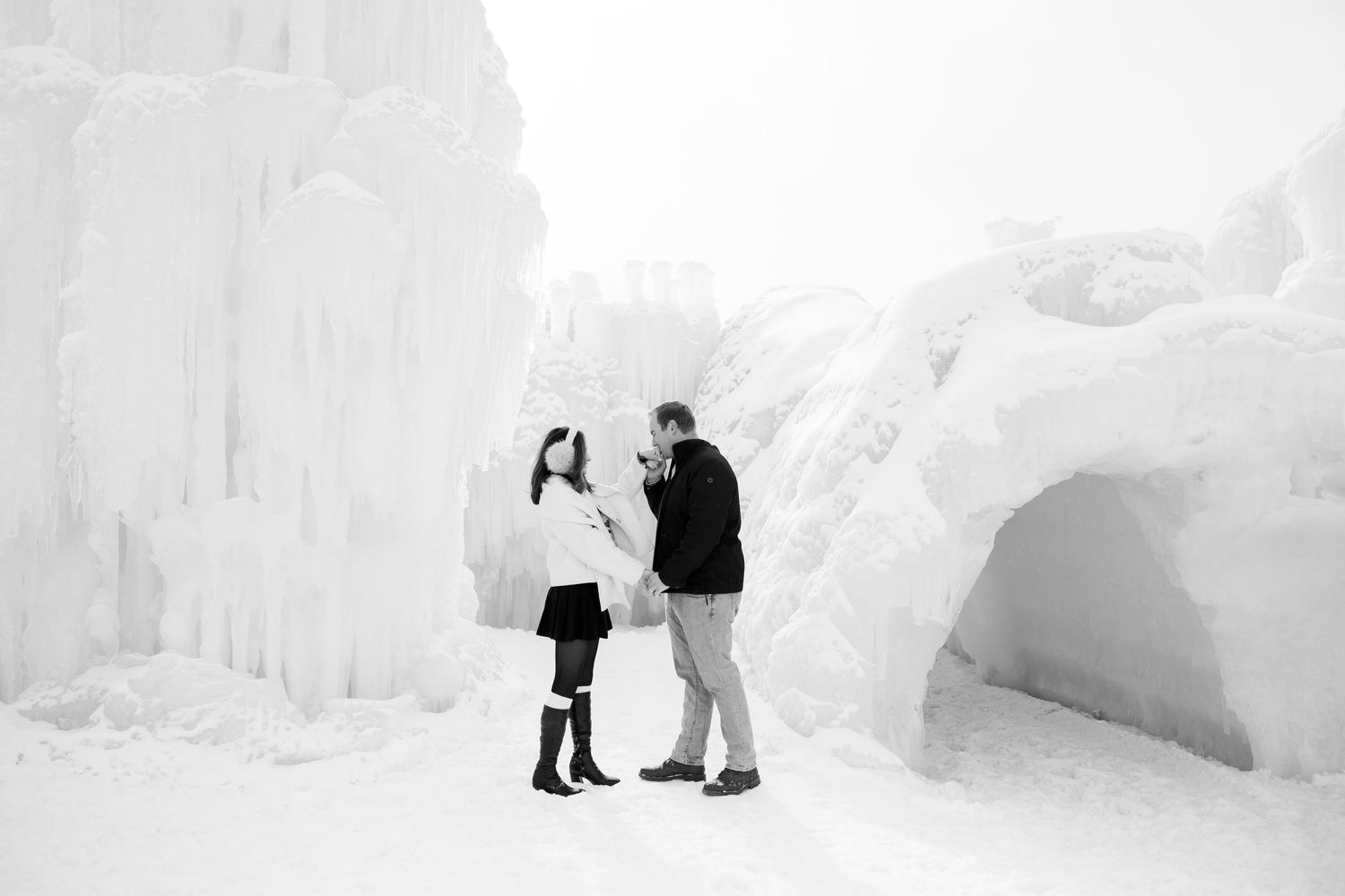 Black and white photo of couple sharing a moment at magnificent ice castle formations.