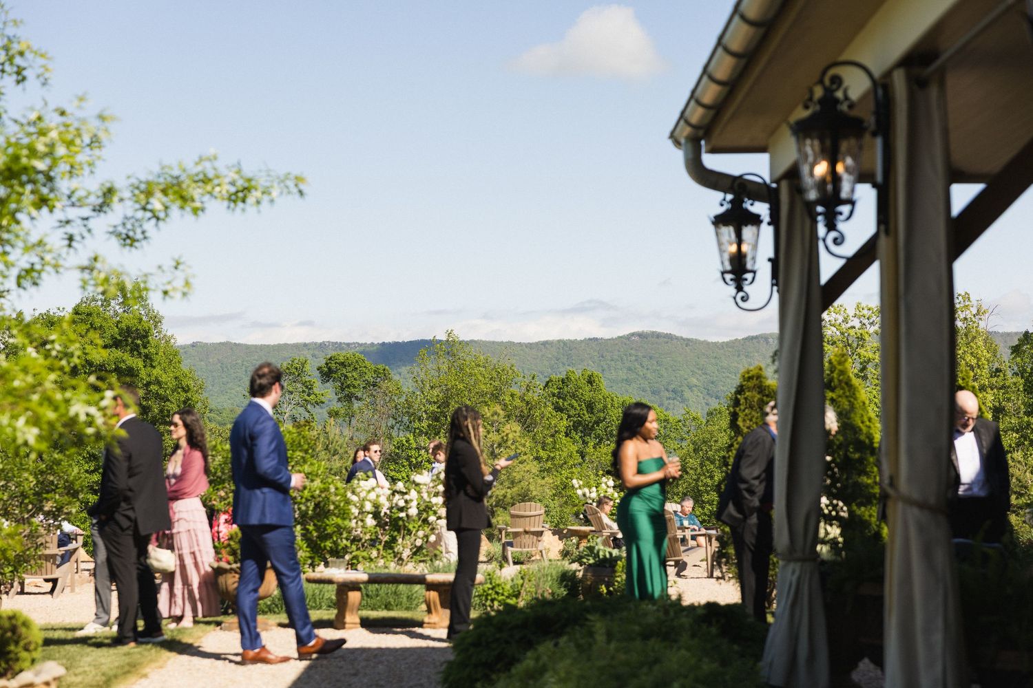 Wedding guests in formal attire socializing on a terrace with stunning Blue Ridge Mountain views in the background.