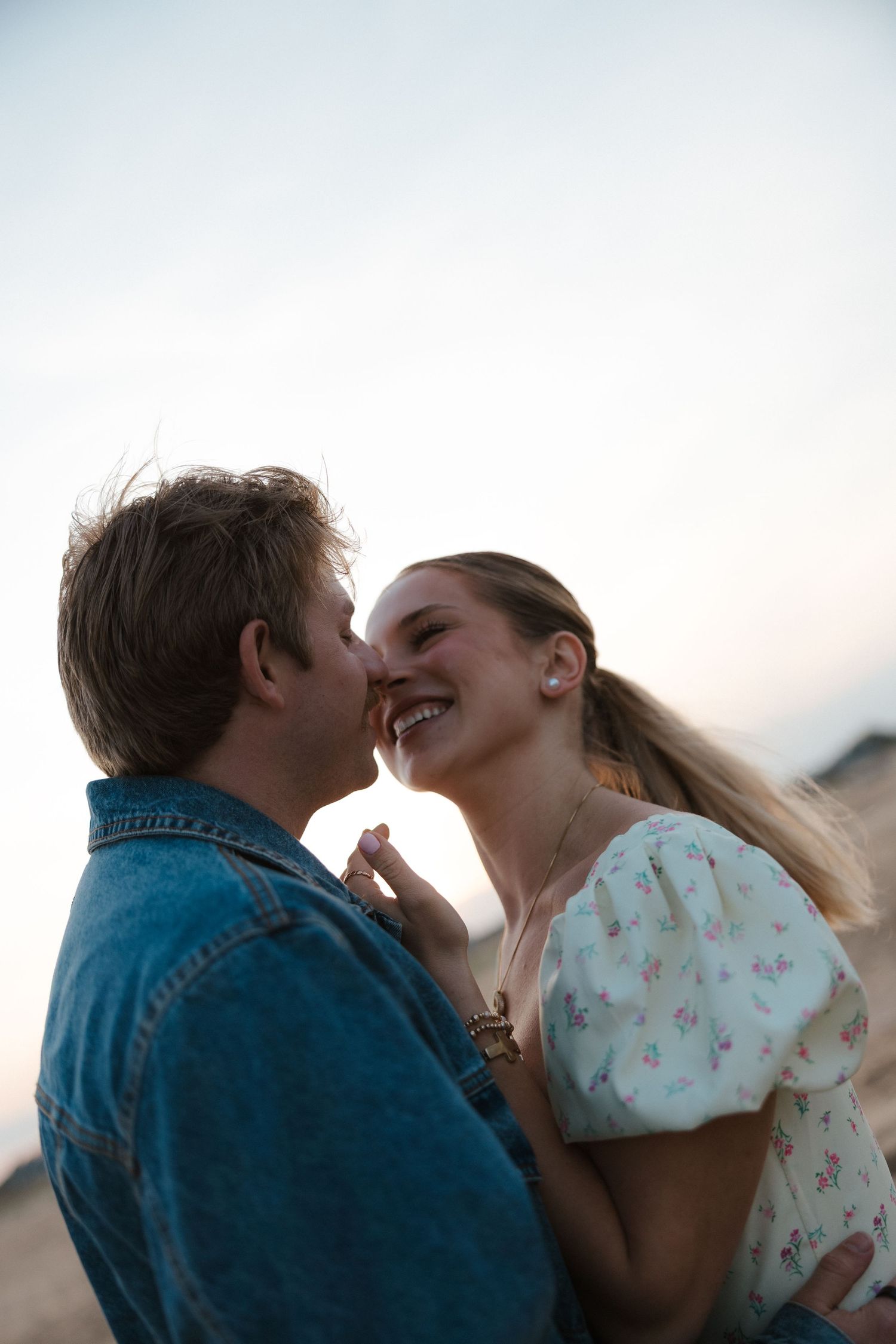 Young couple sharing a romantic moment almost kissing on a beach at sunset.