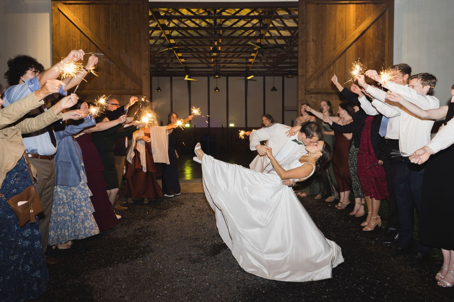 Groom dipping the bride in a kiss under sparklers as they exit their wedding