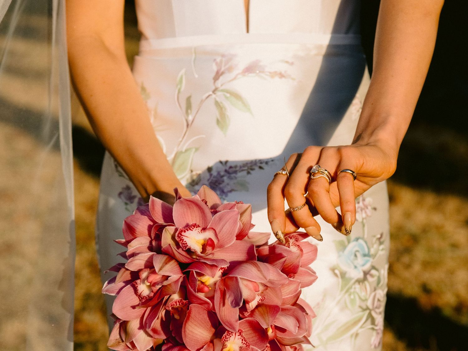 Close-up of pink floral bouquet against white wedding dress fabric.