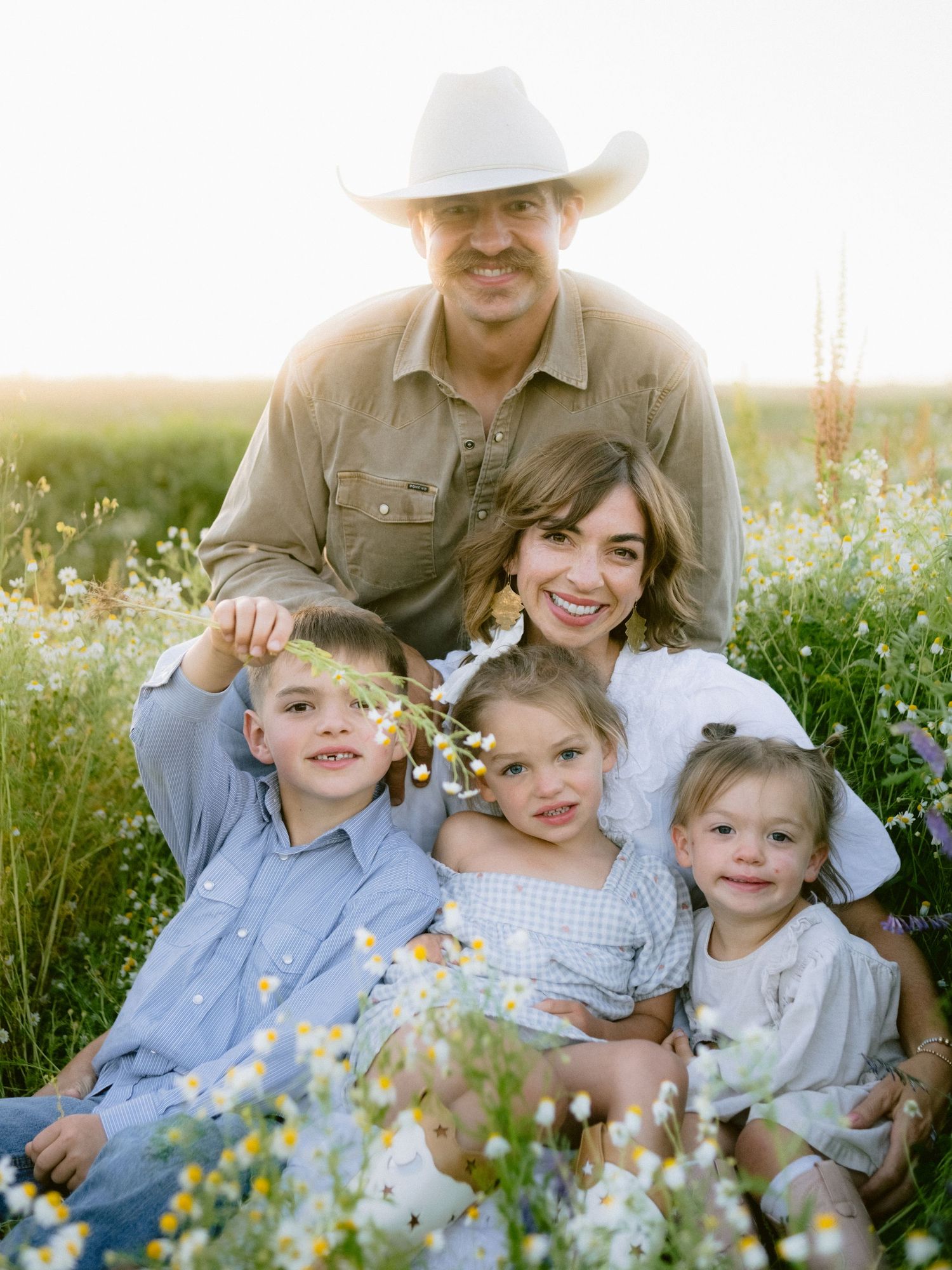 A family sits together in a blooming wildflower field at sunset.