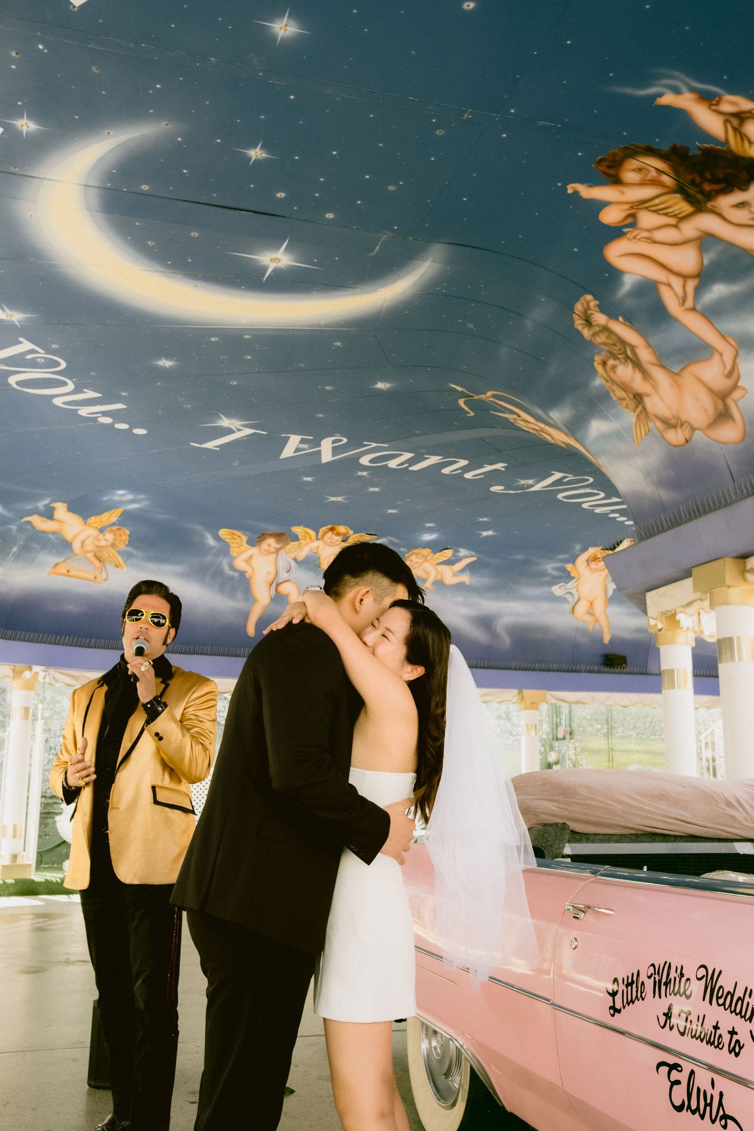Romantic couple poses under a starry painted ceiling with cherub decorations in a wedding chapel.