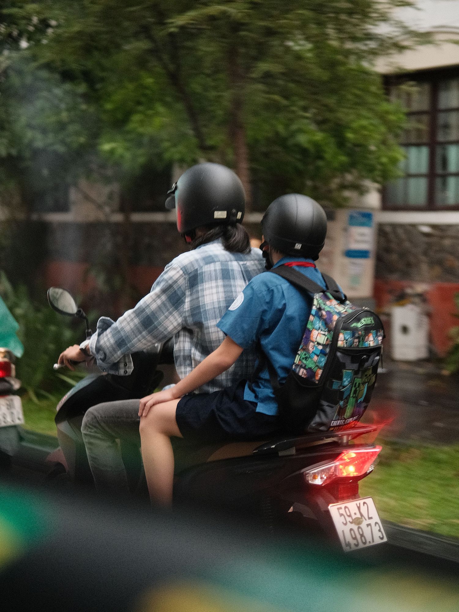 Multiple motorcycles riding in formation on a wet road through green scenery.