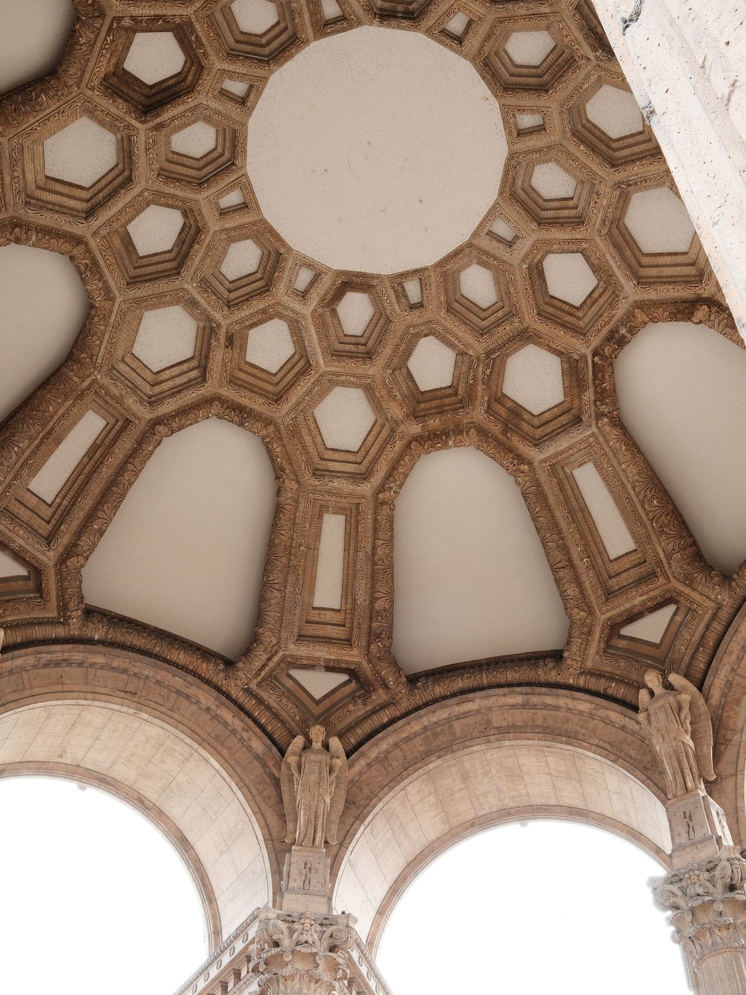 Ornate geometric honeycomb ceiling pattern with arches in beige architectural detail.