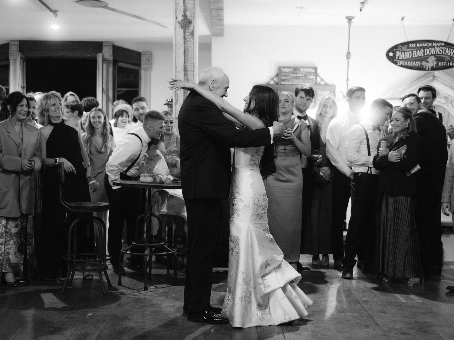 Wedding reception guests dancing and celebrating in a rustic indoor venue.