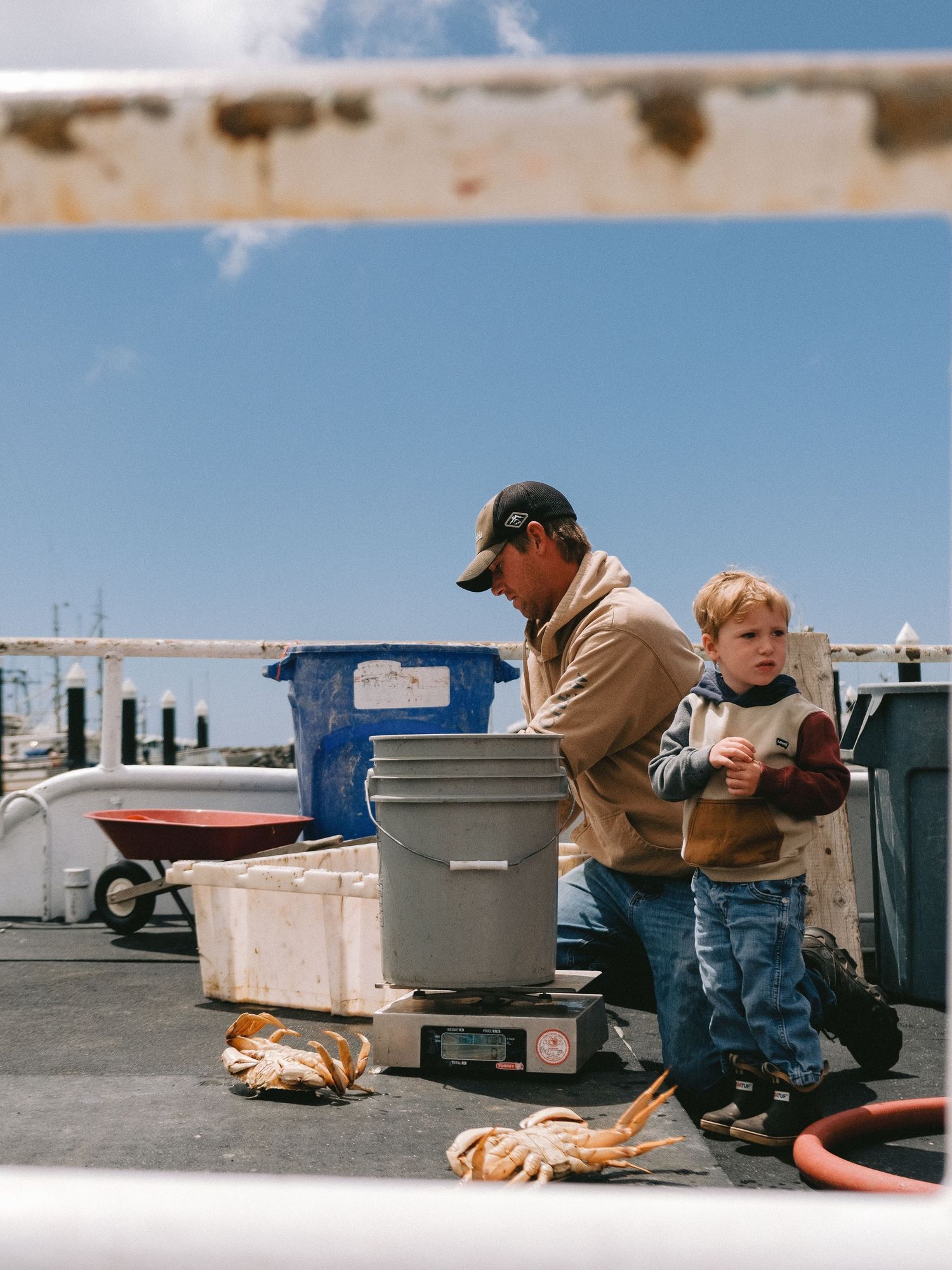People enjoying a casual outdoor meal near storage containers under bright blue sky.