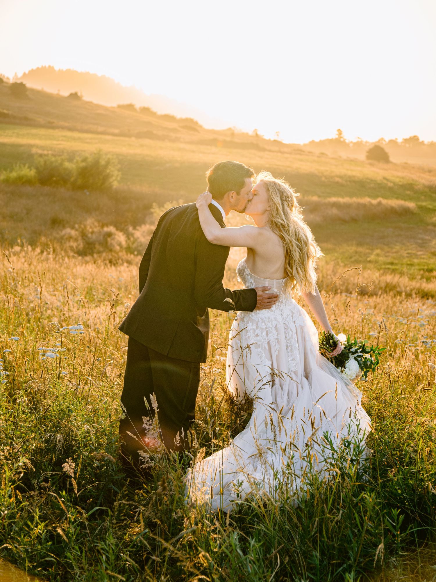 Sunset wedding photography session in a golden meadow with flowing white dress.