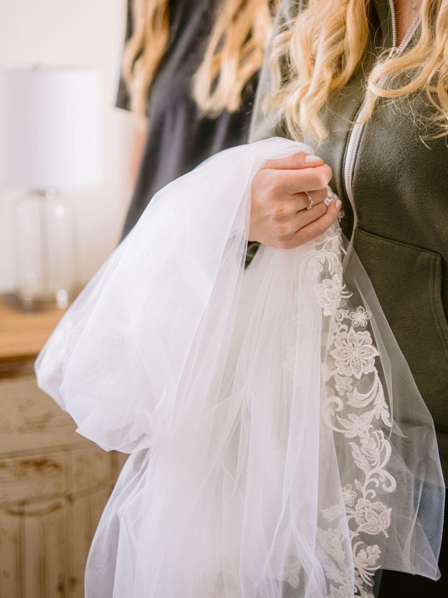 Wedding dress details showing delicate tulle and lace overlay in natural light.