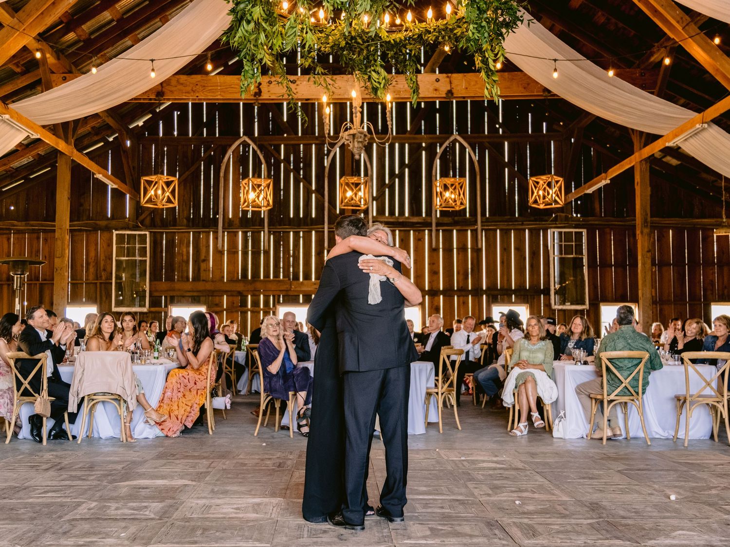 Rustic barn wedding reception venue decorated with string lights and white draping.