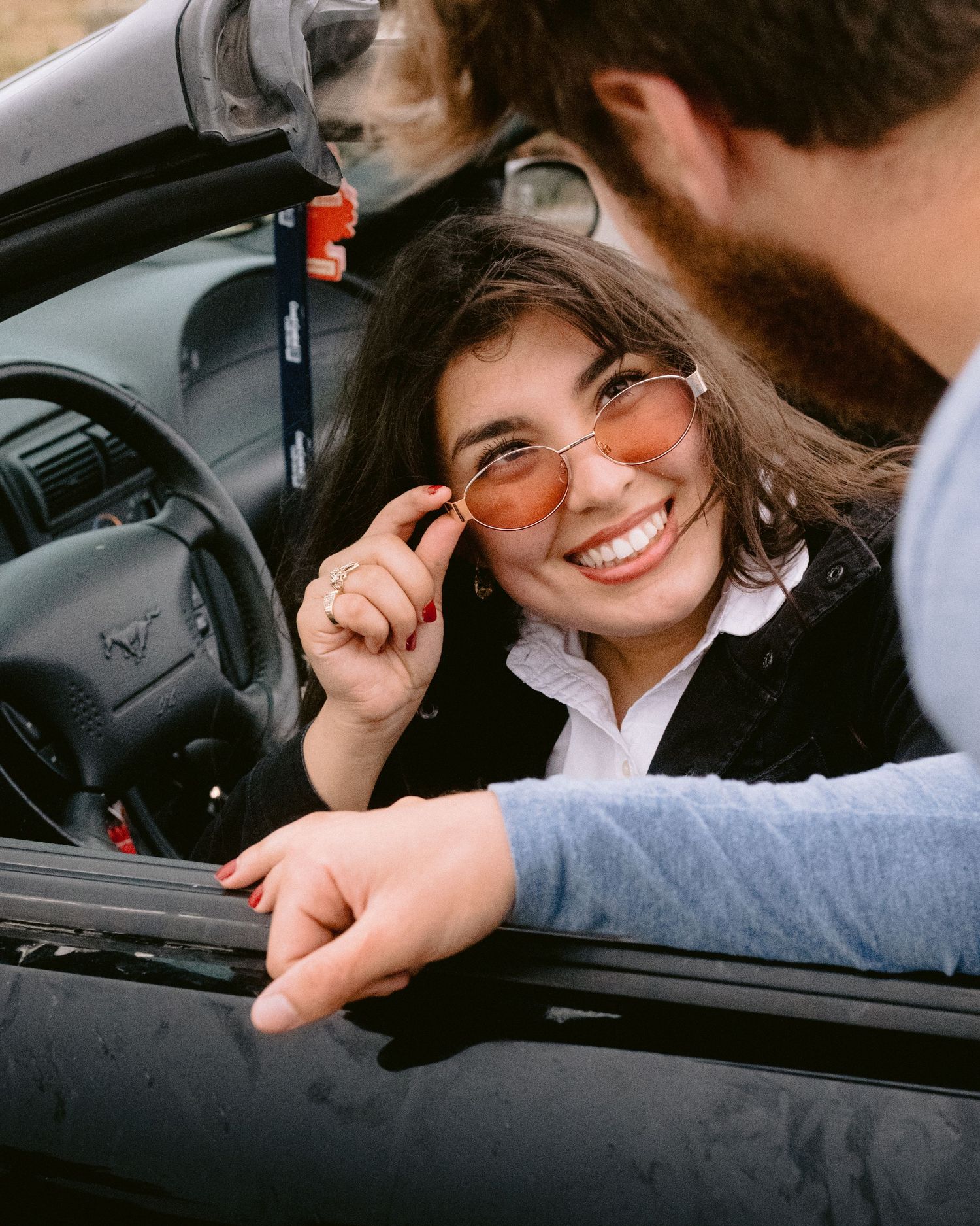 Candid moments of laughter captured inside car on overcast day.