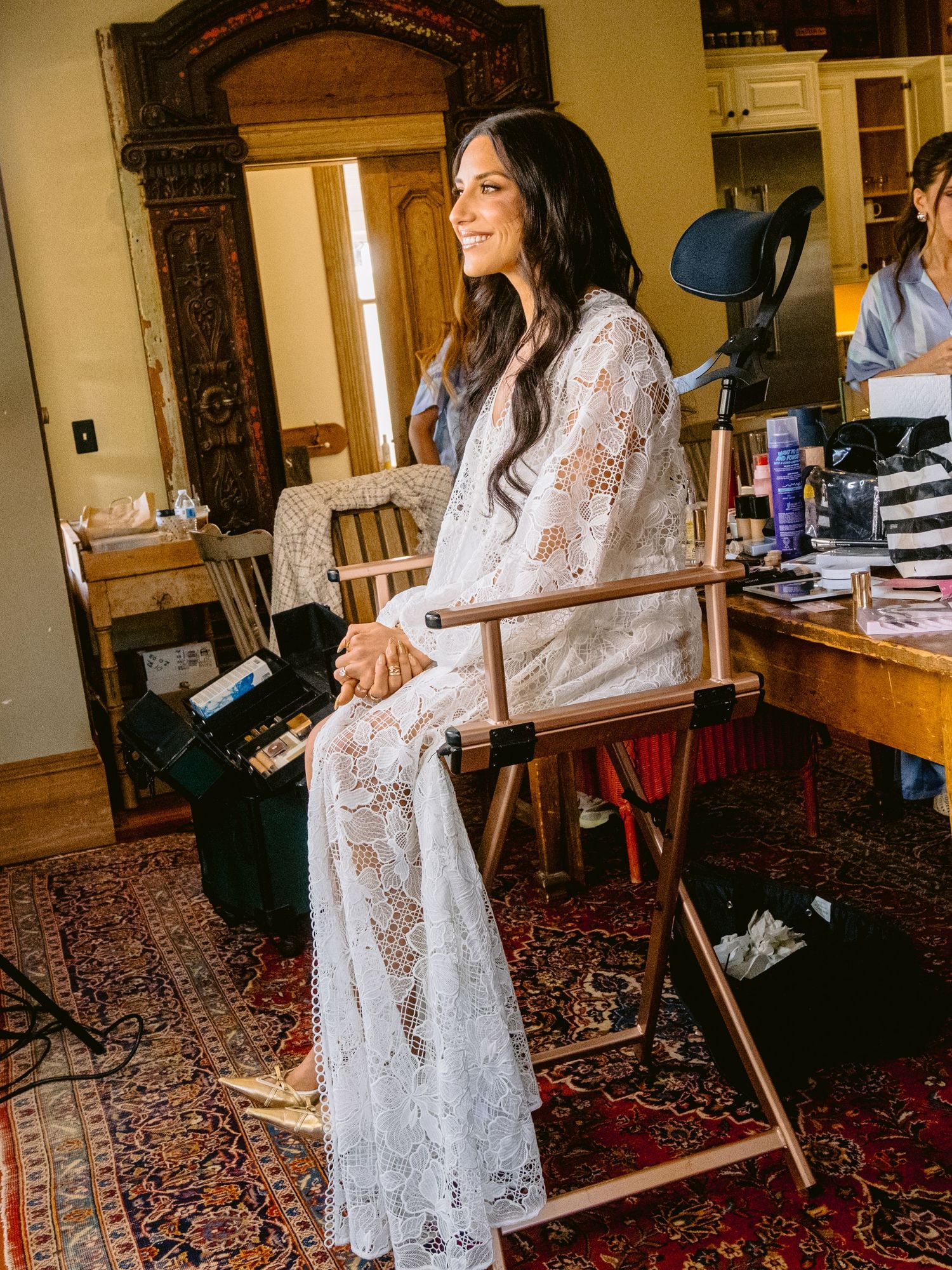A bridal preparation scene with white lace robes in a vintage-style room with ornate carpeting.
