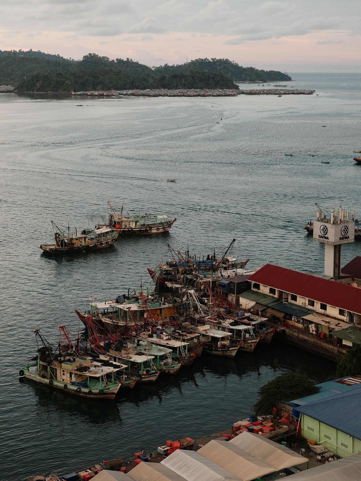 Aerial view of fishing boats docked at harbor during overcast day.