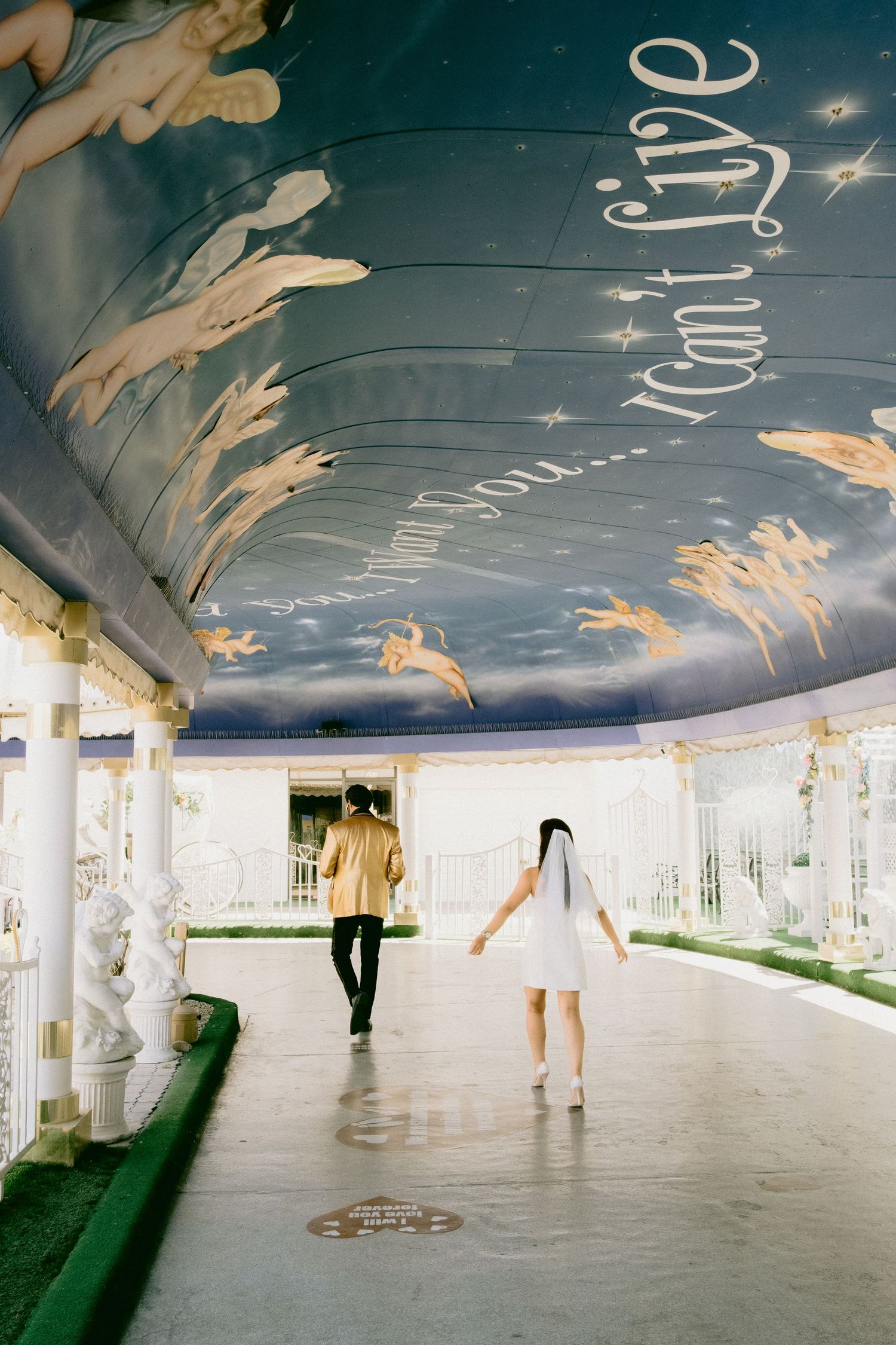 Chapel interior with painted celestial ceiling featuring cherubs and stars in dreamy blue tones.