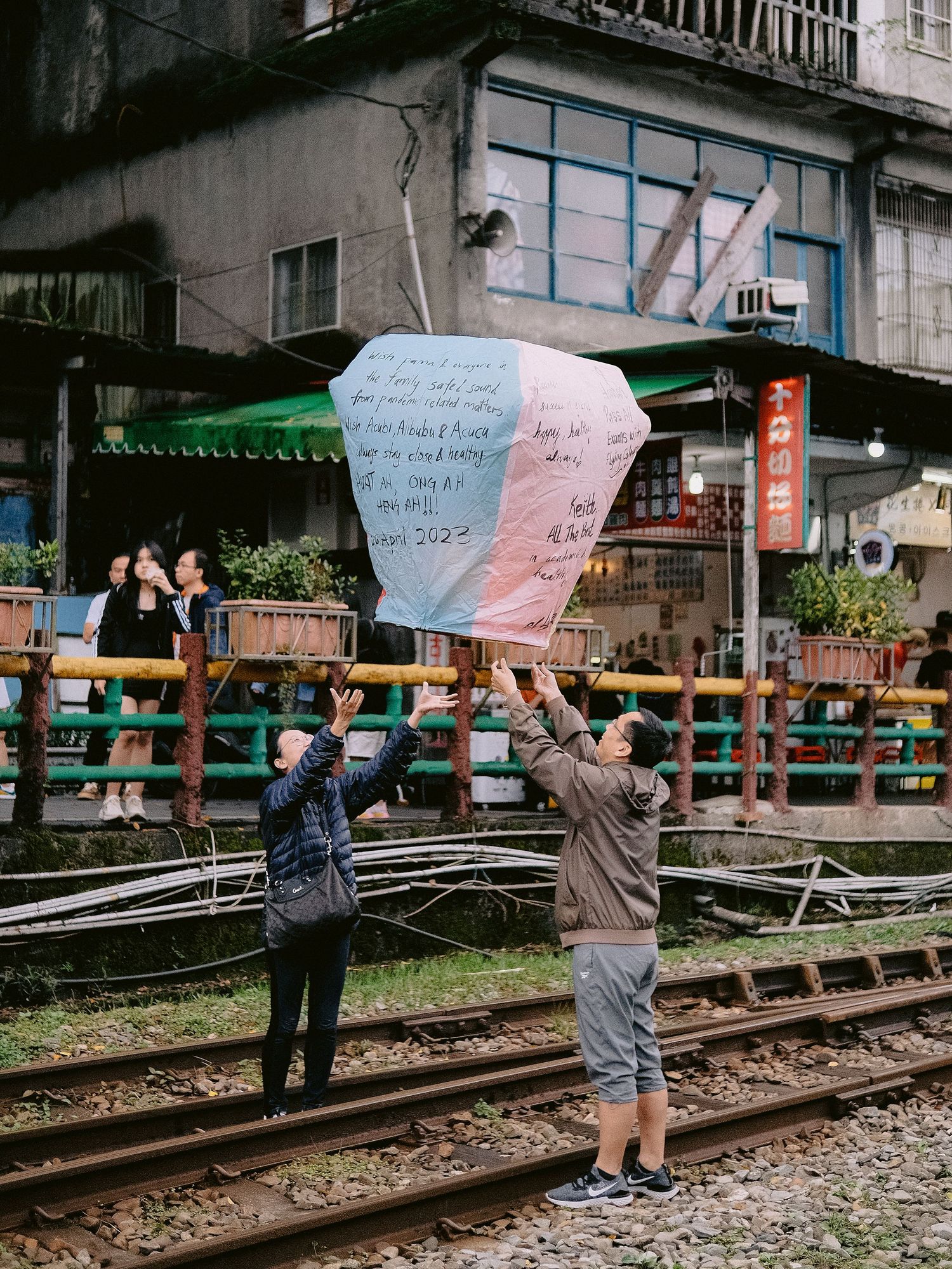 Group holding protest signs while standing along railroad tracks near urban buildings.