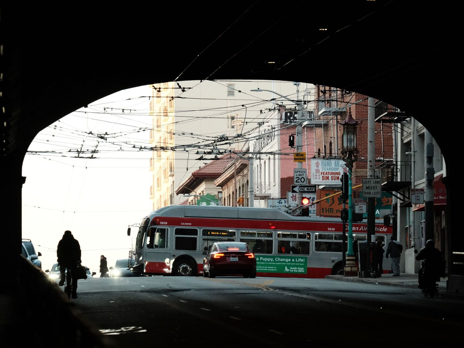Silhouetted urban street scene with public transit vehicles and buildings at dusk.