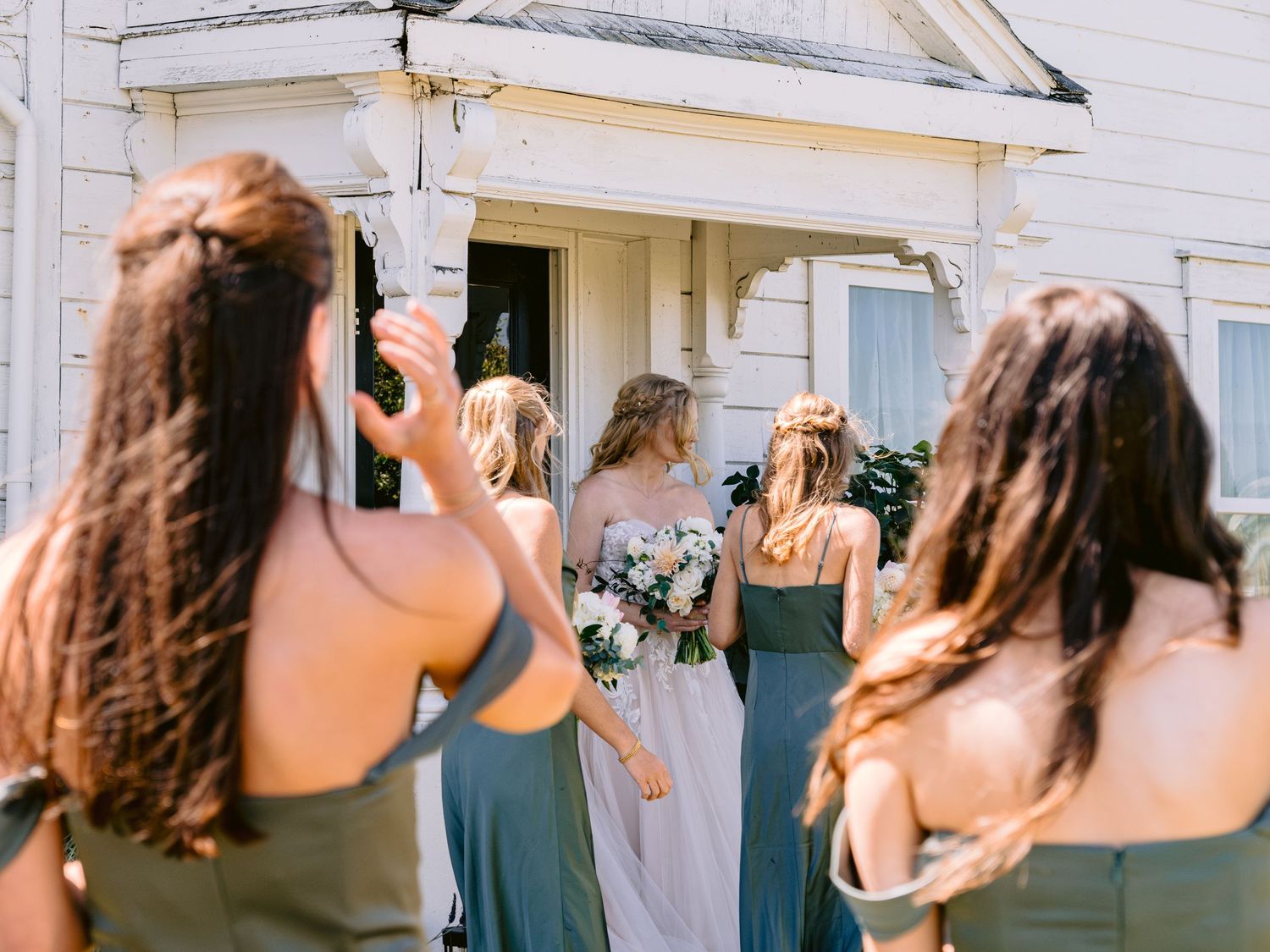 Wedding guests taking photos outside a white building.