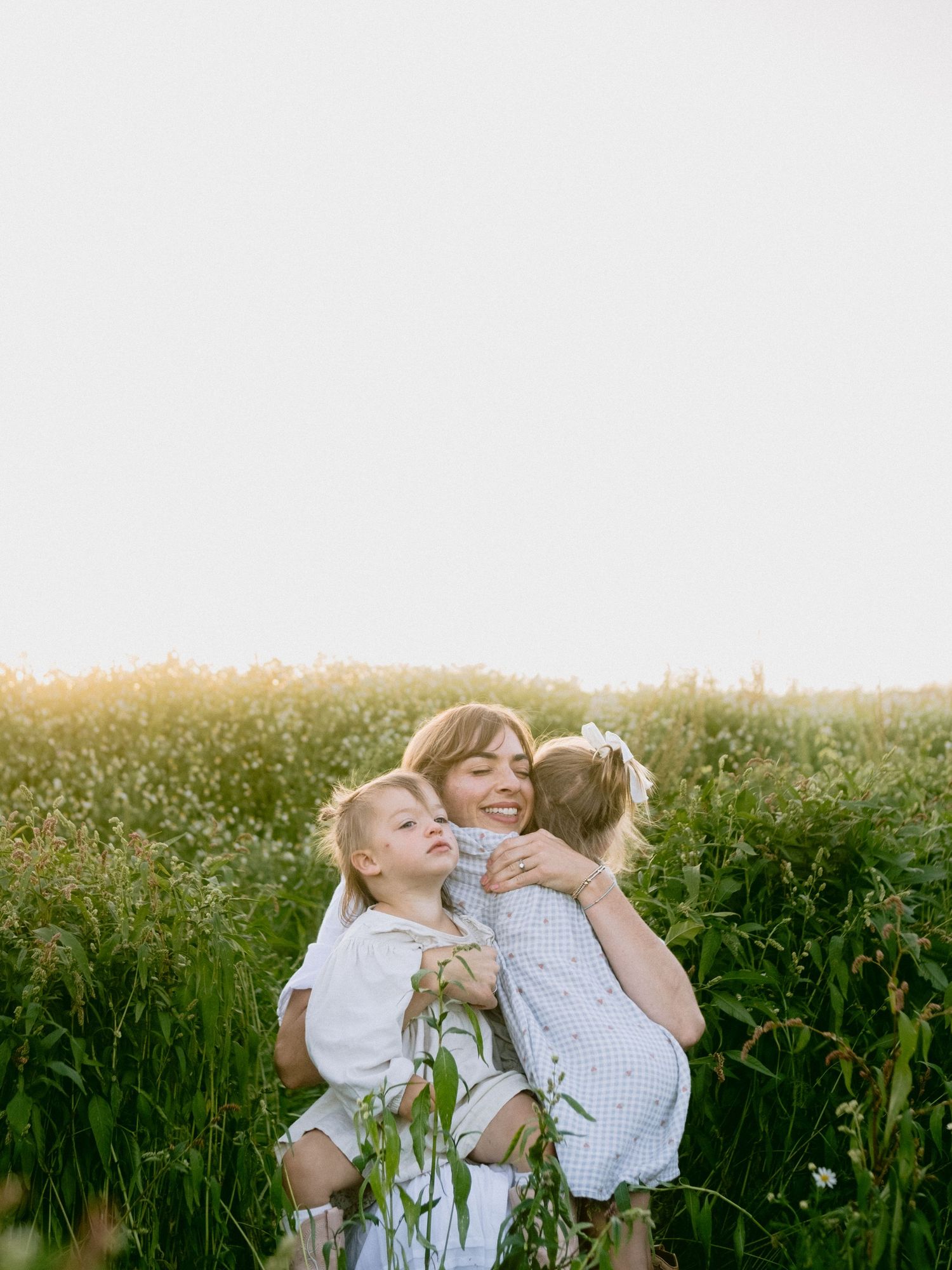Family sharing tender moments in blooming wildflower meadow at sunset.