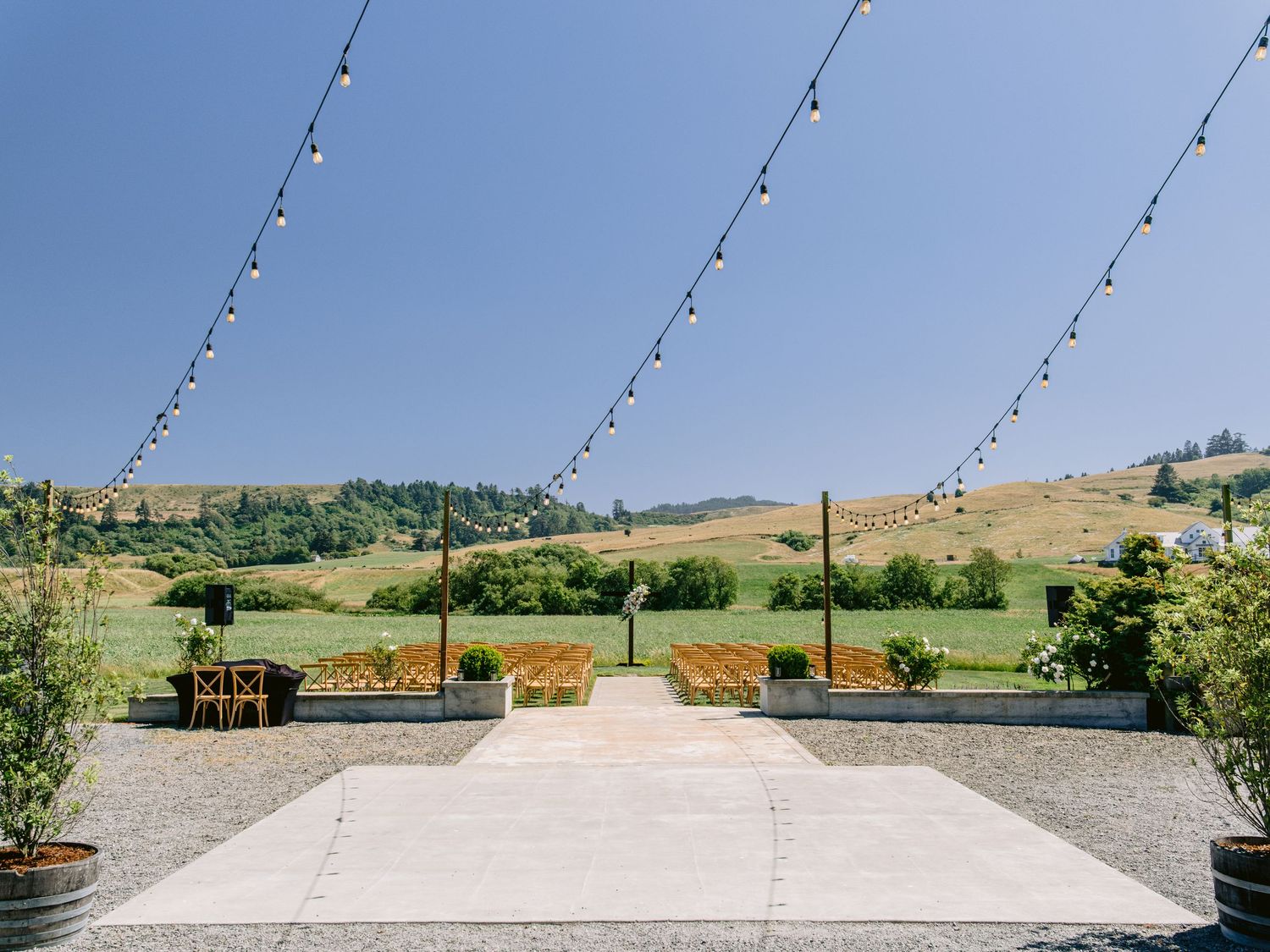 String lights hang above an outdoor patio space with rolling hills in the background.