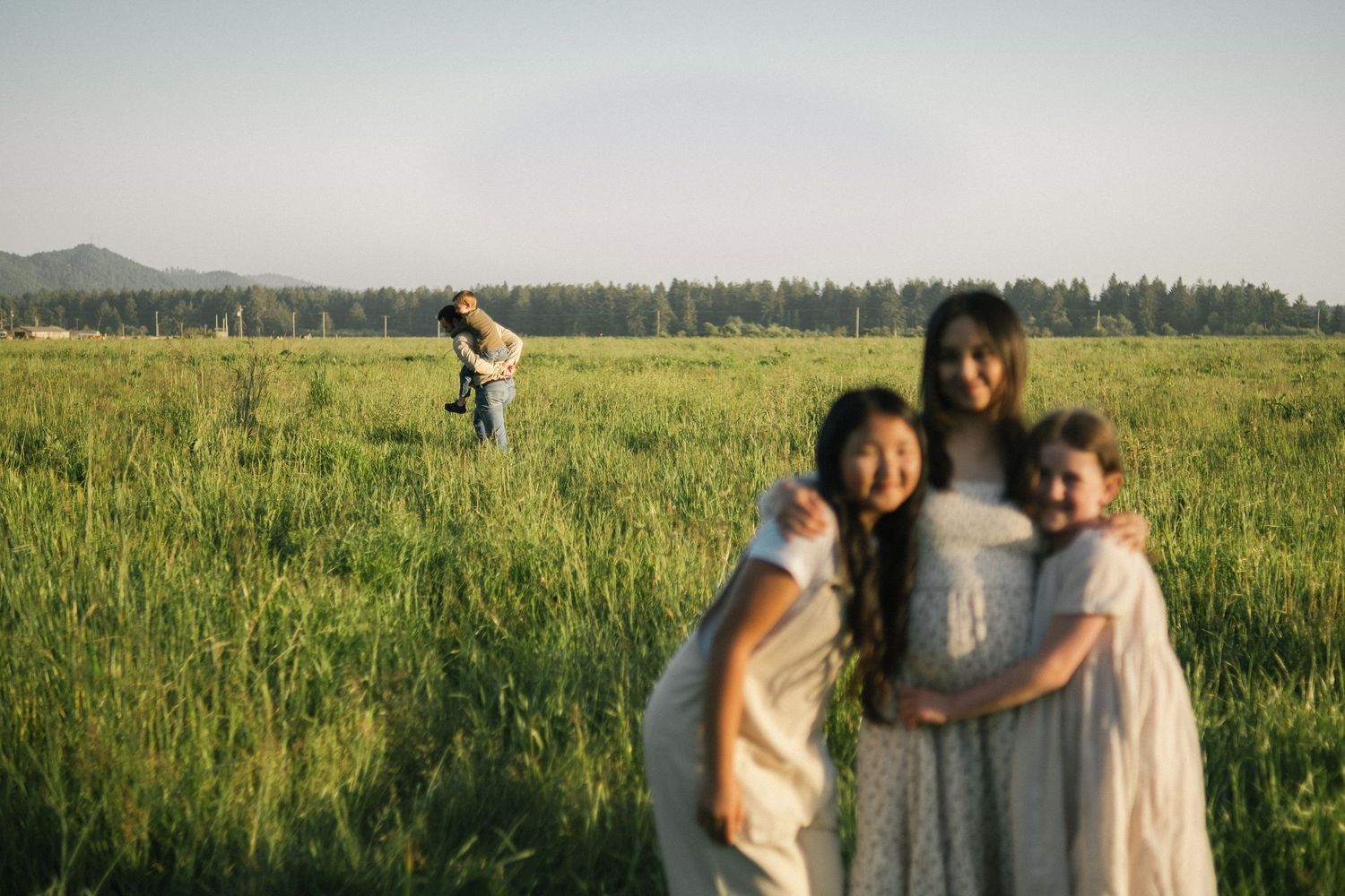 Family walking together through a vast green meadow on sunny day.