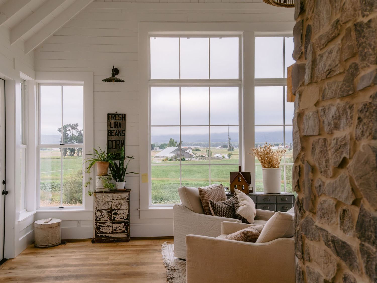 Modern interior of a stone house with large windows overlooking scenic countryside views.