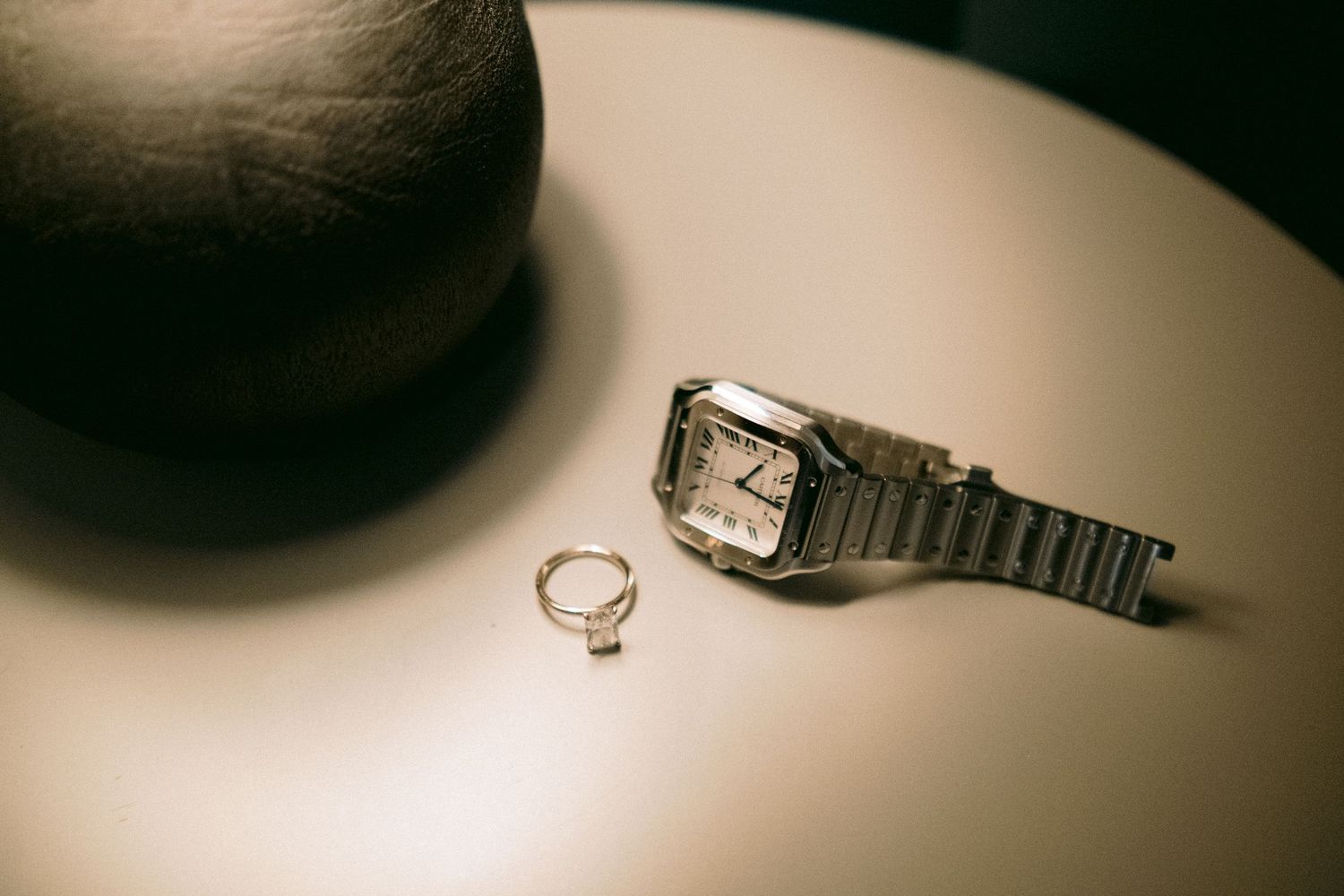Wedding rings displayed on a dark reflective surface with dramatic lighting.
