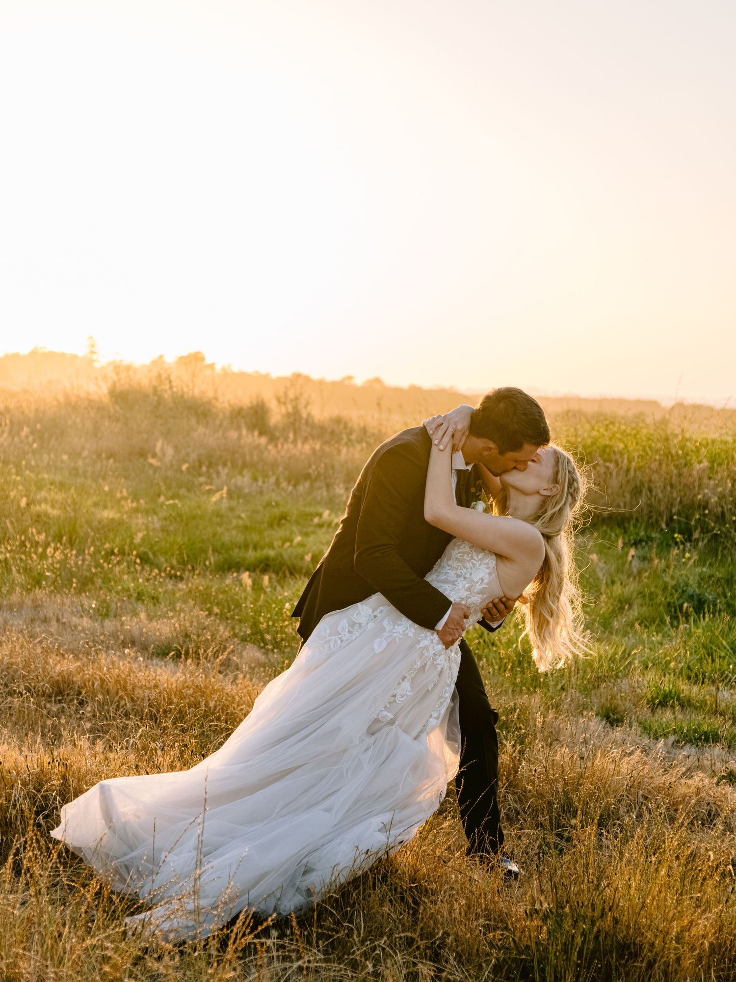 Romantic sunset wedding photos in a golden field with flowing white dress.