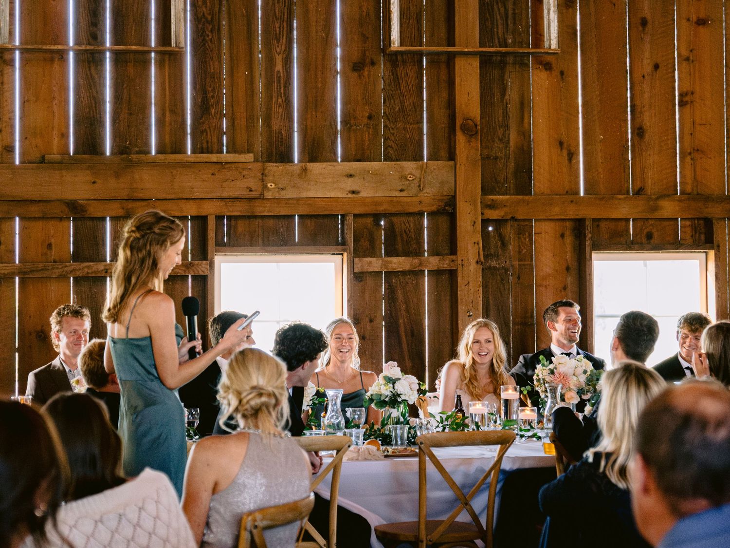 Wedding reception in rustic barn venue with wooden beams and natural lighting.