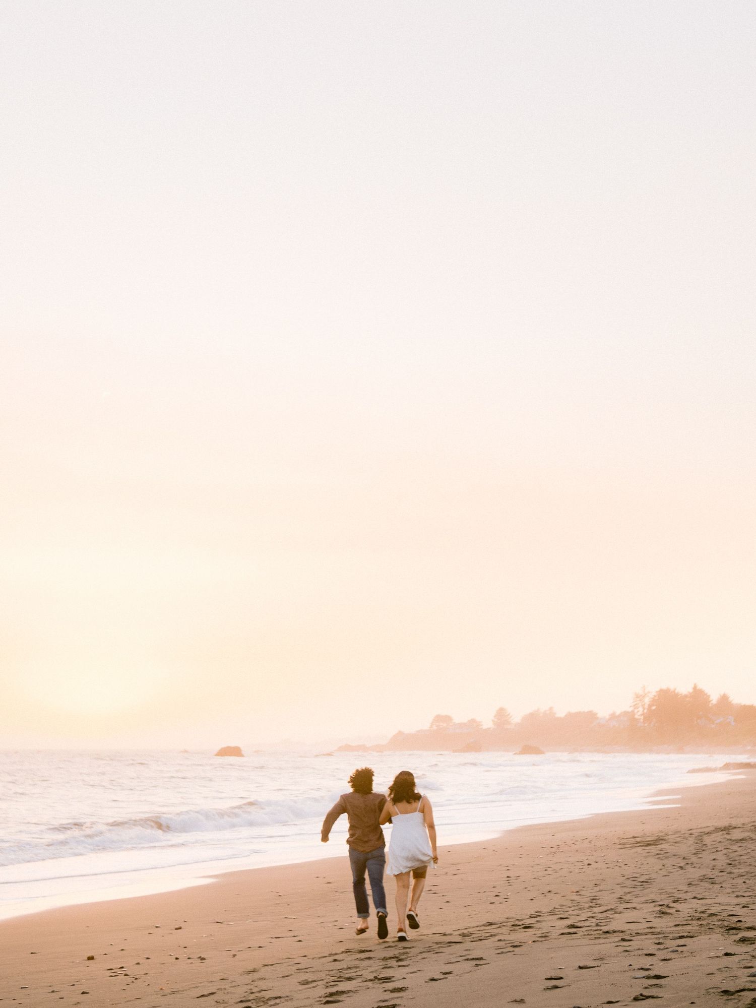 Silhouettes of a couple running and playing on a sunset beach.